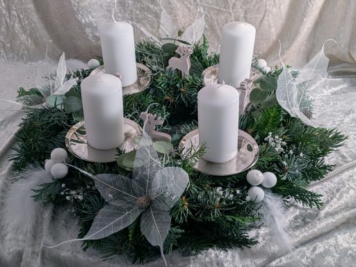 Adventkranz rund weiße Kerze, Spiegelbeeren, Weihnachtssterne und Schleierkraut auf Silbertellern